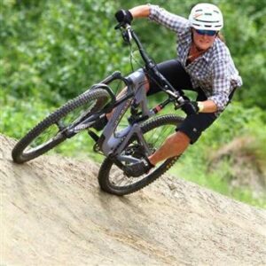 Woman riding a mountain bike on a left leaning slop.